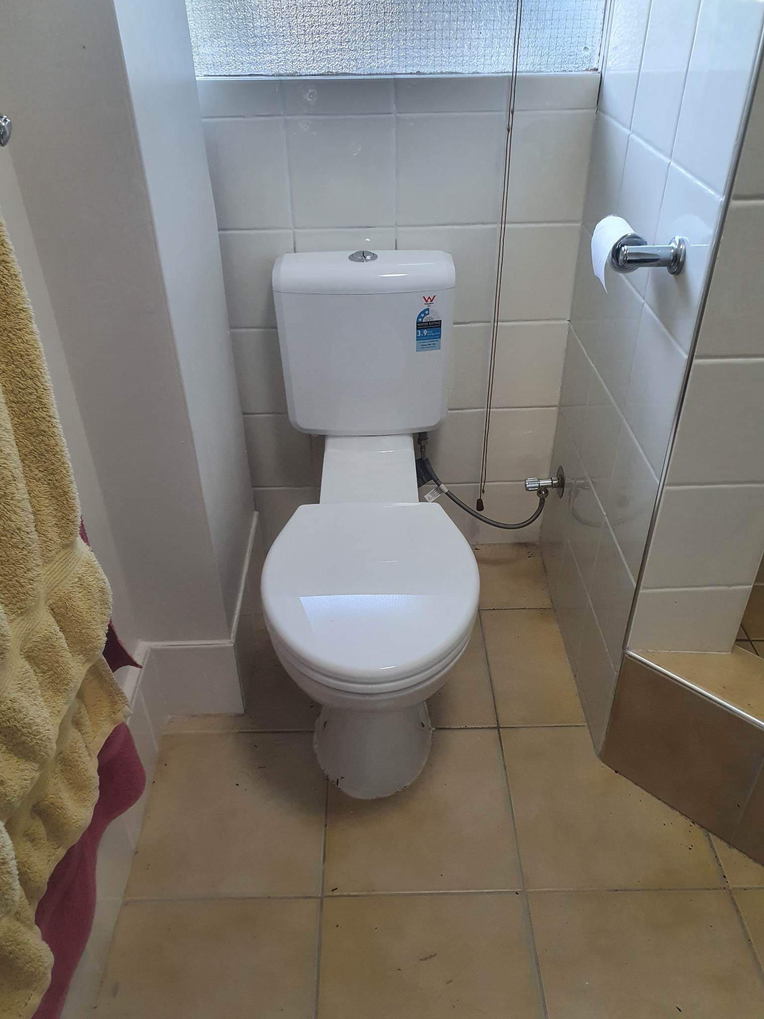 Newly installed toilet suite in a tiled bathroom