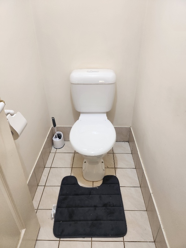 New white toilet suite installed in a narrow tiled toilet room